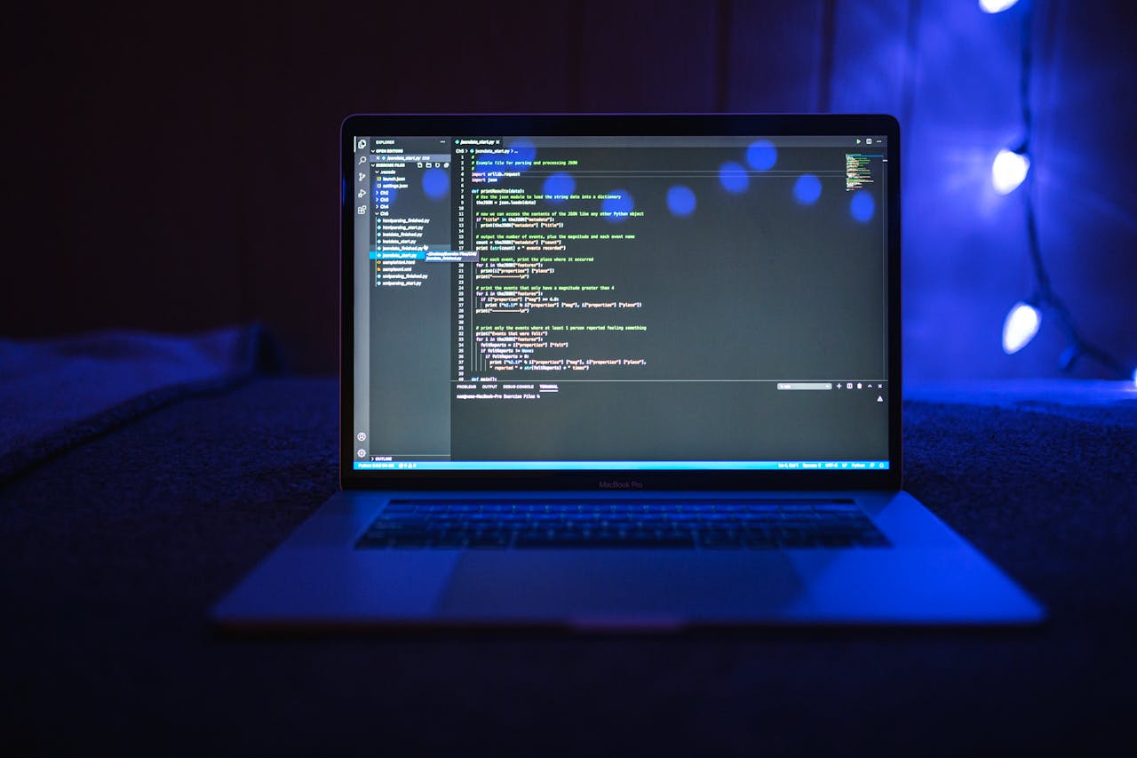 Close-up of a laptop screen displaying code, set against a dark backdrop with blue lighting for a tech-focused ambiance.